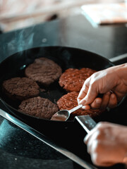Close up on a chef preparing a ground beef hamburger, frying/broiling cheeseburger patties