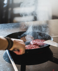 Close up on a chef preparing a ground beef hamburger, frying/broiling cheeseburger patties