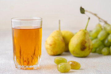 Pears, grapes and juice on white wooden background