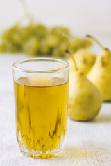 Pears, grapes and juice on white wooden background
