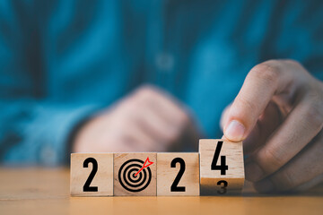 Businessman flipping of 2023 to 2024 on wooden block cube for preparation new year change and start...