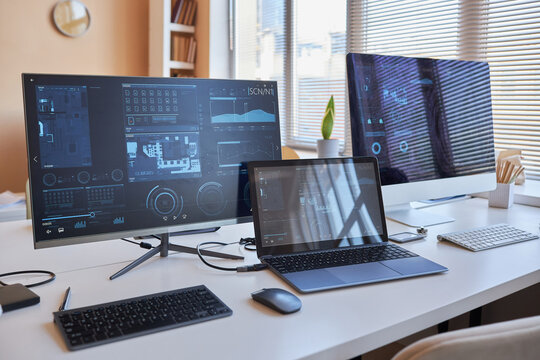 Row of three desktop computers with online graphic data on screens standing on workplace of IT engineer in office environment