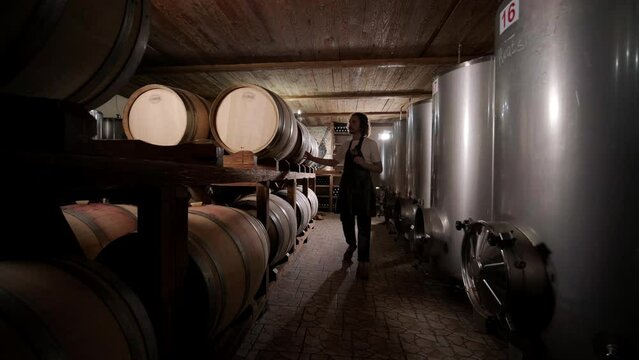 Authentic shot of successful male sommelier is tasting a flavor and checking white wine quality poured in transparent glass in a wine cellar.