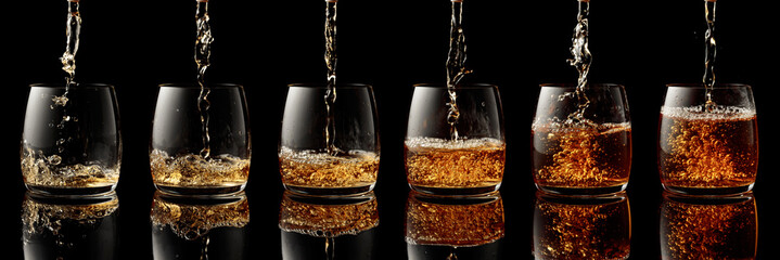Pouring whiskey into a glass on a black background.