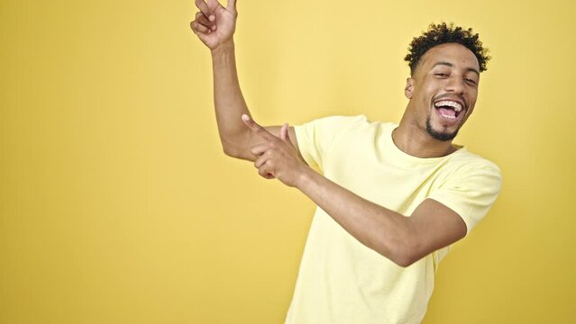 African american man pointing with fingers to the side dancing over isolated yellow background