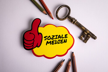 Social Media text in German on a sticky note. White office desk