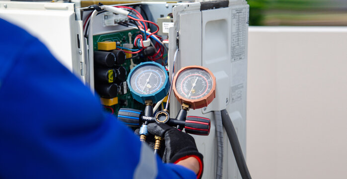 air conditioner technician using manifold gauge checking refrigerant for filling home air conditioning and air duct cleaning and maintenance outdoor compressor unit.