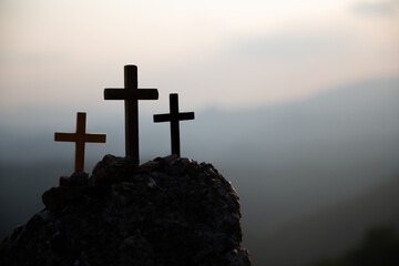 The three holy crosses of Jesus Christ shining through the red sky and clouds and bright rays background. Silhouette cross on Calvary mountain sunset background. Easter concept