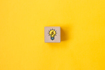 Light bulb on wooden cube on yellow background. Thinking new ideas concept