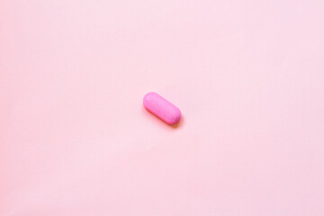 Pink medicine pill on pink background. Top view of mineral pill.