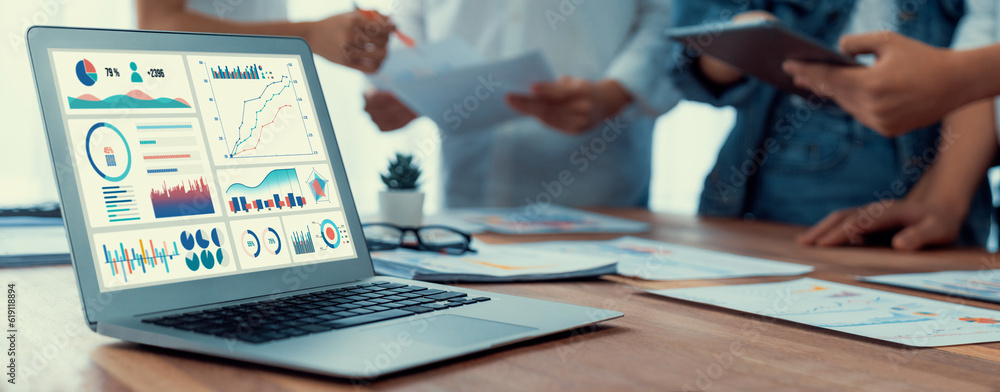 Poster Focus BI power dashboard display on laptop screen with blurred background of analyst team analyzing business financial data using BI Fintech software for business insight. Panorama shot. Scrutinize