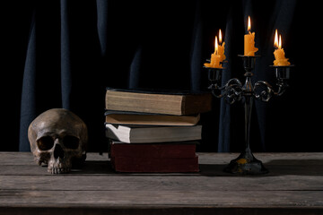 Dark and Atmospheric Still Life: Skull, Candle, and Antique Books in a Macabre Arrangement.