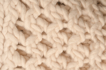 A fragment of beige knitted fabric, knitted from white sheep wool.