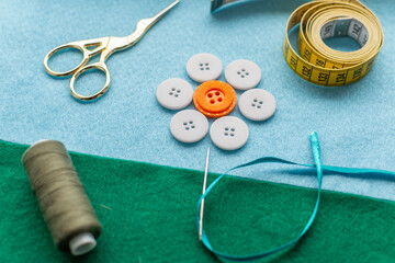 Sewing theme creative composition: flower made of buttons, needle on felt fabrics.