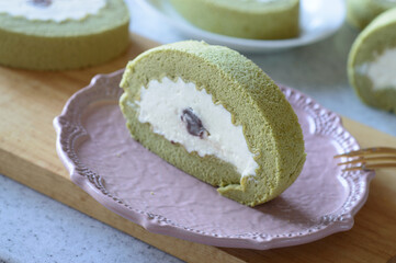 a plate of matcha roll cake with red bean and whipped cream filling 