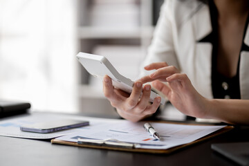 Business woman using a calculator to calculate numbers on a company's financial documents, she is analyzing historical financial data to plan how to grow the company. Financial concept.