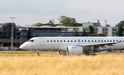 white new passenger airplane taking off from runway without logo with copy space, panning shot

