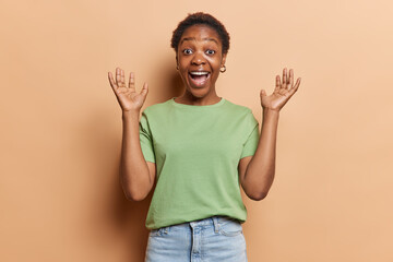 Photo of African woman showcases her elation by raising her palms and exclaiming loudly gets...