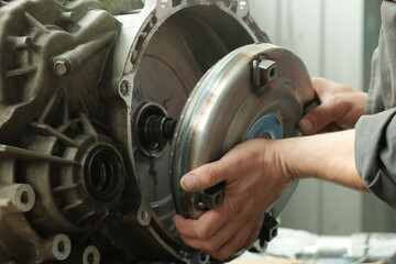 Car service. Automatic transmission of a passenger car. Close-up. An auto mechanic installs a...