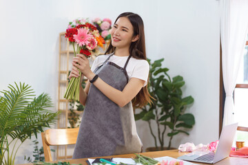 Florist concept, Female florist holds colorful gerbera to prepare for making flower bouquet in shop - Powered by Adobe
