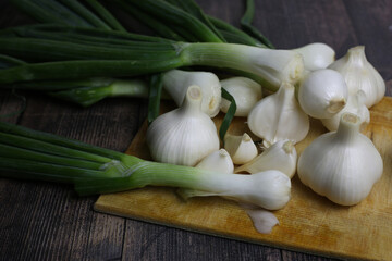 Fresh garlic and onions on the table. Kitchen still life with heads of garlic. Vegetables ingredients for a recipe on a kitchen board