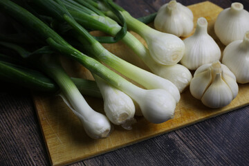 Fresh garlic and onions on the table. Kitchen still life with heads of garlic. Vegetables ingredients for a recipe on a kitchen board