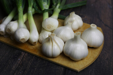 Fresh garlic and onions on the table. Kitchen still life with heads of garlic. Vegetables ingredients for a recipe on a kitchen board