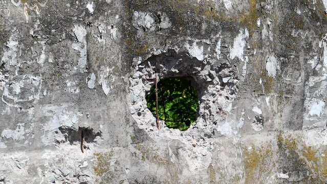 Broken cement wall or fence. Stone grunge odd wall with a hole. Damaged grungy crack and broken concrete wall.