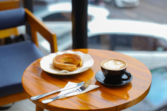 Latte coffee and pastry on a wooden table with space