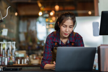 Close-up store owner smiling face when typing on laptop computer, because they are responding...