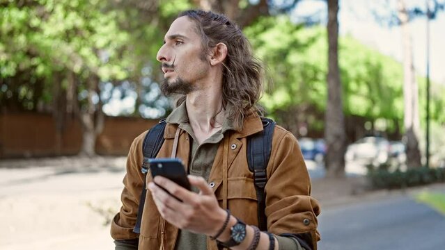 Young hispanic man tourist using smartphone at park