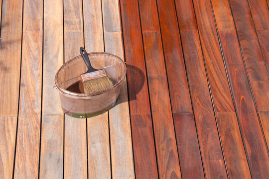 Ipe wood deck renovation treatment and maintenance concept, paint brush on the bucket with oil