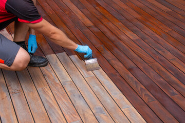 Wood deck refreshing, worker hand applying terrace oil with a brush