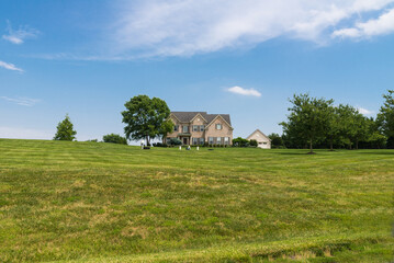 Obraz premium large private brick country house with a green trimmed lawn. Sunny summer day and blue sky.