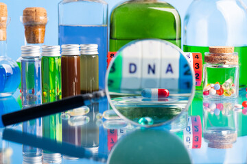 DNA pill on the background of a laboratory table with medicines and preparations. View through a magnifying glass. On a blue background. Selective focus.