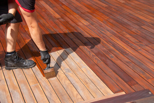 Oiling wooden terrace with a brush, wood deck staining
