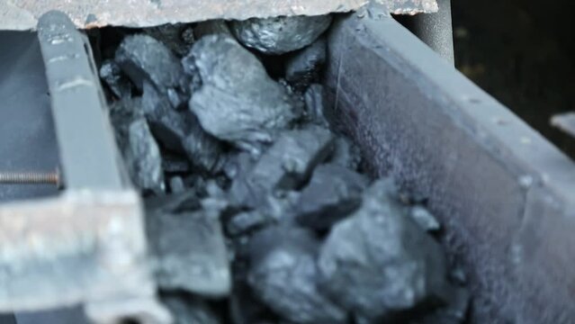 Closeup of charcoal or bituminous coal moving on a roller belt conveyor machine