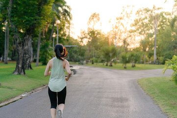 Obraz premium Fit Asian young woman jogging in park smiling happy running and enjoying a healthy outdoor lifestyle. Female jogger. Fitness runner girl in public park. healthy lifestyle and wellness being concept