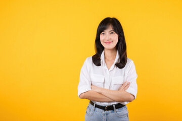 Young Businesswoman. Portrait asian woman happy smiling, posing confident, cross arms on chest, standing against yellow studio background. Smart young entrepreneur advertising products and services.