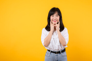 Young beautiful asian woman happy smile wearing white shirt and denim jean plants over yellow isolated background smiling confident showing and pointing with fingers teeth and mouth. Dental concept.