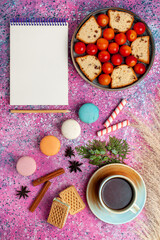 Fototapeta na wymiar top distant view delicious sliced cake with sour fresh plums french macarons and cup of tea on the pink desk pie sweet biscuit cookie sugar fruit