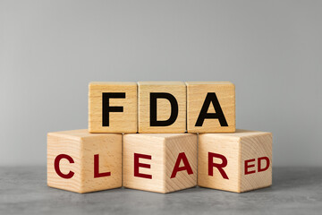 FDA cleared, words on wooden blocks. Beautiful gray background, business concept, Confirmation of inspection and registration of drugs and medical devices used in medicine