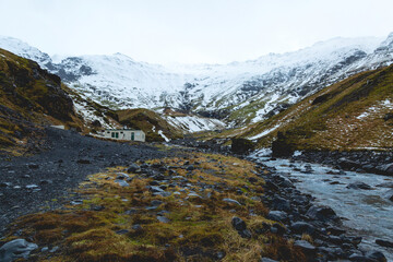 Une rivière sur le lieu touristique de Seljavallalaug avec au fond, des montagnes enneigées. 