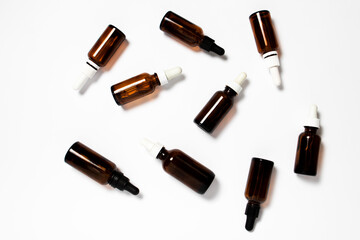 Glass dropper bottles with a pipette on white background, Flat lay top view
