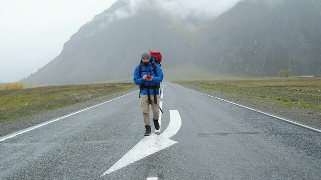 Travel man with phone to search gps location on journey adventure in contryside road. Vacation, holiday or happy walking tourist on internet for roadmaps or directions online. Beautiful foggy