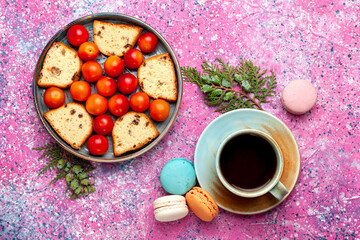 top view delicious sliced cake with sour fresh plums macarons and tea on the pink background pie sweet sugar bake biscuit cookie fruit