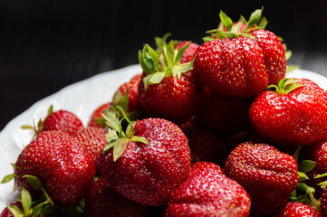 Ripe, juicy strawberries on a white plate