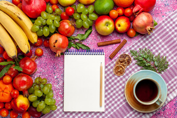 top view fresh fruit composition colorful fruits with cup of tea and notepad on pink background fruit fresh mellow color ripe