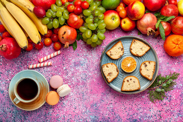 top view fresh fruit composition colorful fruits with cup of tea cakes and french macarons on pink desk fruit fresh mellow color ripe