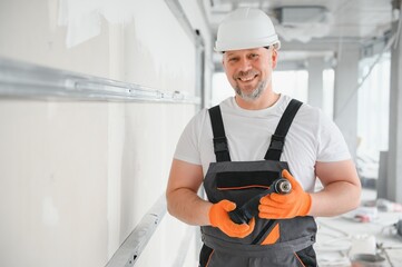 man drywall worker or plasterer putting mesh tape for plasterboard on a wall using a spatula and...